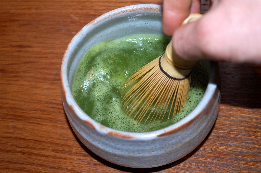 Image of a person whisking green tea.