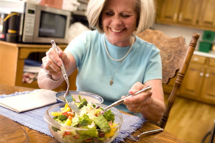 Happy woman eats a bowl of healthy vegetables and salad between intermittent fasting windows.