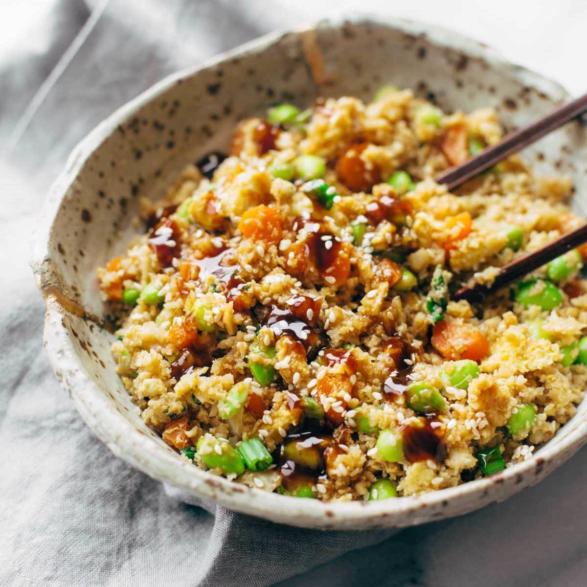 Savory Cauliflower Symphony: A Delightful Fusion of Riced Cauliflower, Colorful Vegetables, and a Medley of Exquisite Asian Flavors in this Irresistible Fried Rice Delicacy.