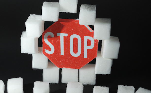 A conceptual image depicting how to curb sugar cravings with sugar cubes and a stop sign.