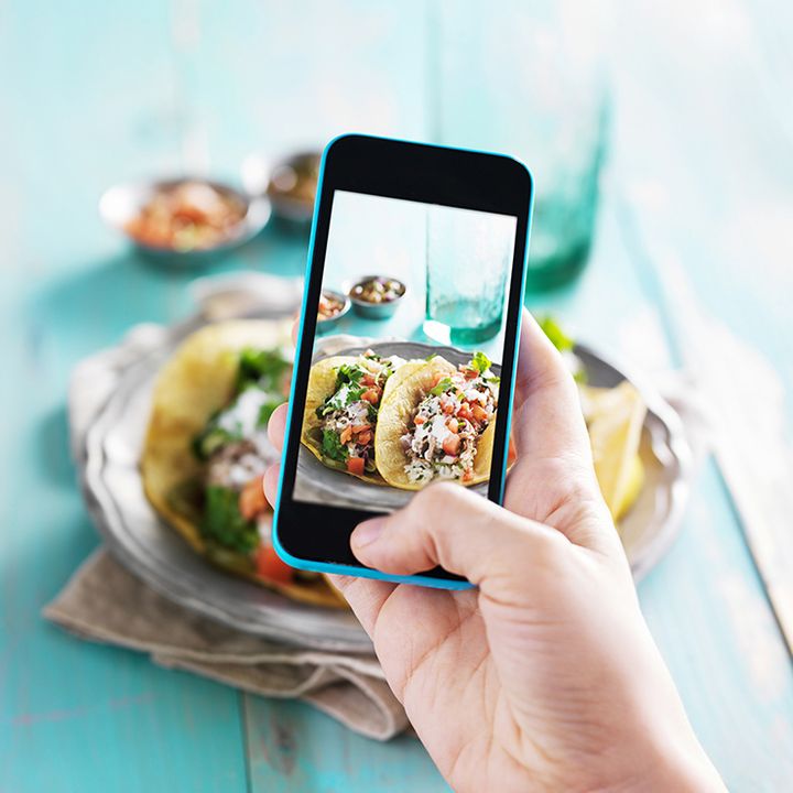 Person using a smartphone to capture an image of tacos, demonstrating the convenience of food tracking with SnapCalorie.